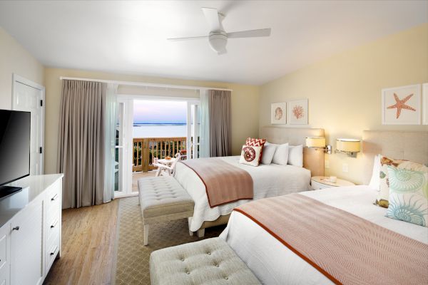 Sanderling Resort's beach-themed bedroom with two beds, a TV, and a balcony overlooking the sea.