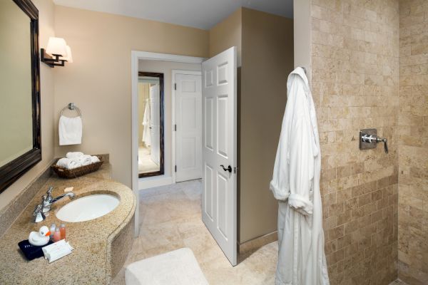 Sanderling Resort's tidy guest bathroom with a sink, mirror, and hanging white robe.
